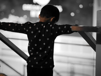 Rear view of woman standing by railing