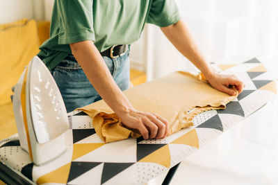 Close-up of an unrecognizable woman ironing linen on an ironing board.