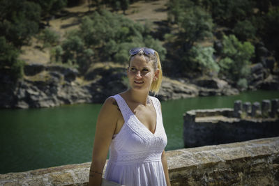 Portrait of woman standing against water