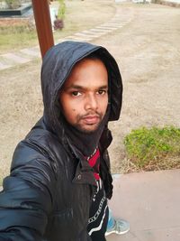 Portrait of young man standing in park during winter