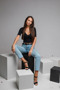 Portrait of smiling young woman against wall