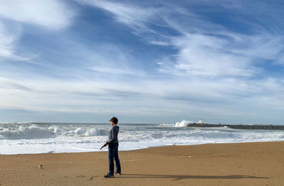 Full length of child standing on beach against sky