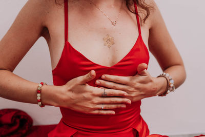 Midsection of woman holding hands against white background