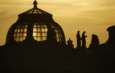 Silhouette people against orange sky