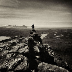 Man standing on rock by sea against sky