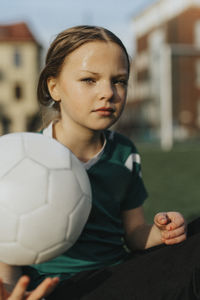 Portrait of female athlete with soccer ball at sports field