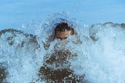 Young man swimming in splashing sea