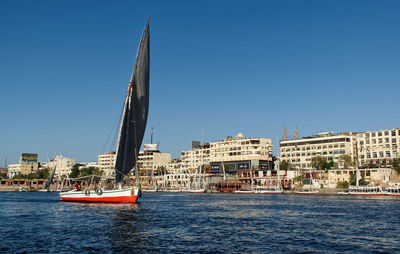 Boats in sea against clear blue sky