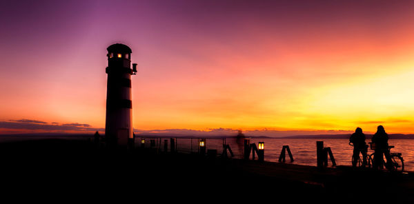 Silhouette people on beach against sky during sunset