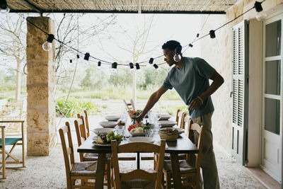 Young man setting dining table for dinner party at patio