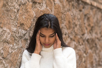 Portrait of beautiful young woman against wall