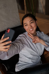 Portrait of young woman sitting on sofa at home