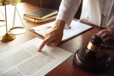 Midsection of woman reading book on table