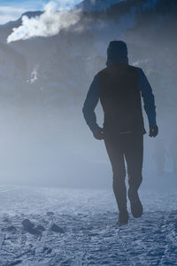 Rear view of man standing in sea during winter