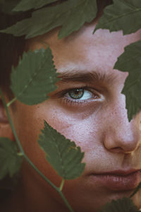 Close-up portrait of woman with green leaves