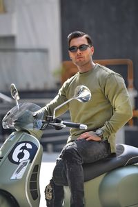 Portrait of young man riding motor scooter on street