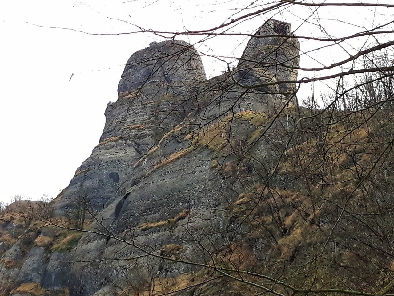 LOW ANGLE VIEW OF ROCK FORMATION BY MOUNTAIN AGAINST SKY