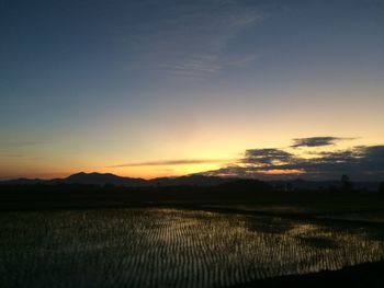 Scenic view of silhouette field against sky during sunset