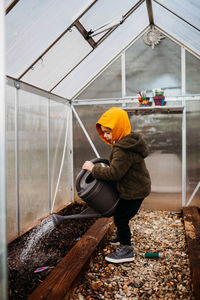 Young boy watering seeds in backyard green house