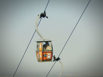 Low angle view of overhead cable car against sky