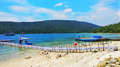 Pier at beach against mountain at coral island