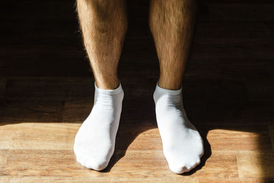 Men's hairy legs in white socks on a wooden floor