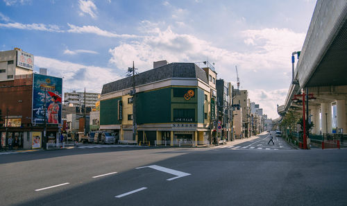 Road by buildings in city against sky