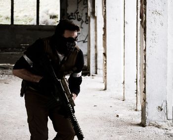 Terrorist with gun standing by wall