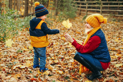 Side view of a boy wearing autumn leaves