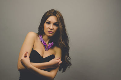 Portrait of young woman standing against wall