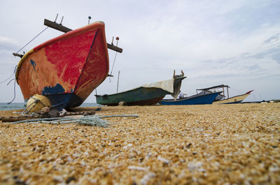 Boat moored on beach against sky