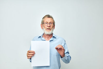 Portrait of smiling man holding paper currency against white background