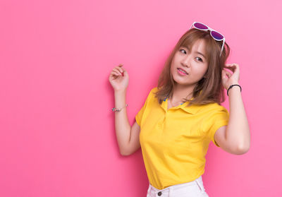 Close-up of beautiful woman standing against pink background