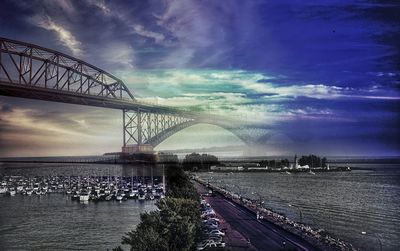 Bridge over river against cloudy sky