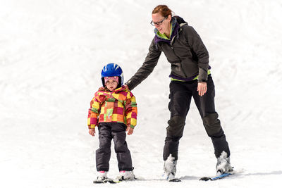 Full length of mother and son skiing on snow