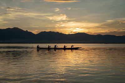 Silhouette people on boat against sky during sunset