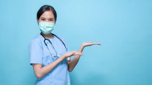 Portrait of teenage girl standing against blue background