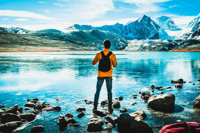 Rear view of man standing on rock against sky