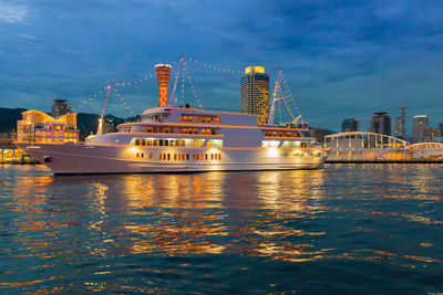 Illuminated ship in sea against sky in city