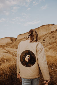 Woman with umbrella on field against sky