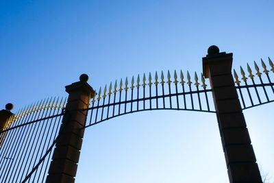 Low angle view of silhouette fence against clear blue sky