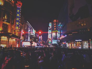 Crowd on illuminated city against sky at night