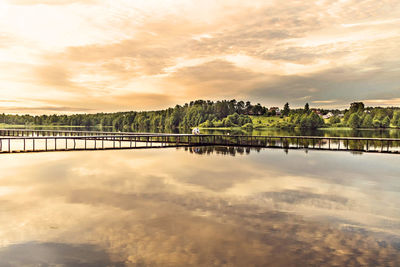 Scenic view of lake by building against sky during sunset