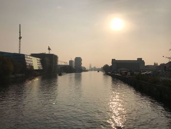 River by city against sky during sunset