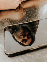 Reflection of woman in mobile phone on table