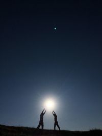 Silhouette people standing on field against sky