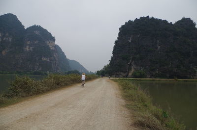 Rear view of people on road by mountain against sky