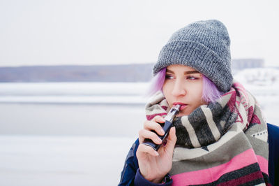 Close-up of young woman using phone while standing on snow
