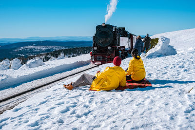 People on snow covered mountain against sky