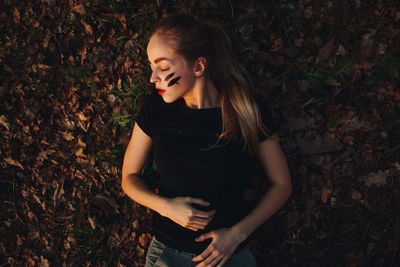 Beautiful young woman standing by tree during autumn